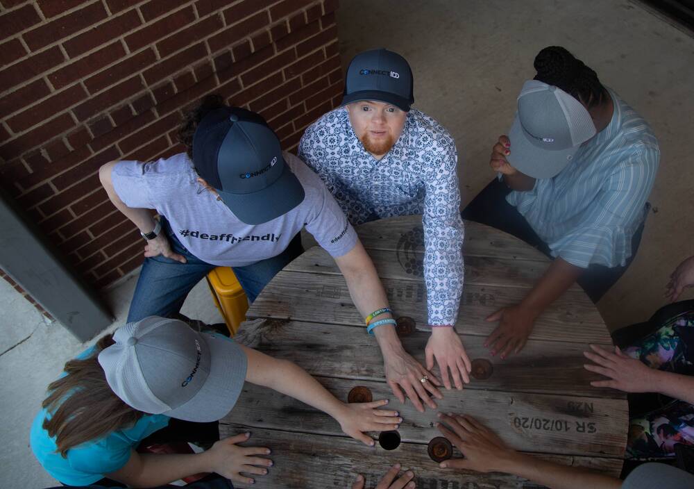 Overhead view of a group in ConnectIDD caps stacking hands on a table.